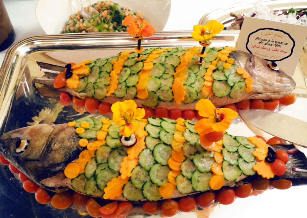 Poisson cuit décoré avec des concombre, des carottes et des fleurs comestibles.